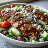 Fresh Mediterranean flavors shine in this colorful Greek salad bowl with grilled chicken and crisp vegetables.  