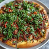 Crispy Turkish Lahmacun Pizza, featuring spiced lamb topping and vibrant sumac, ready to be rolled.