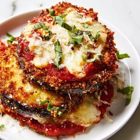A close-up of a layered Eggplant Parmesan with crispy eggplant and rich tomato sauce, ready to serve.