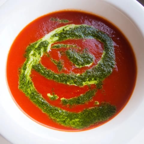 Steaming bowls of tomato soup with basil pesto swirl paired with grilled cheese for a cozy lunch.