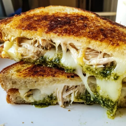 Freshly grilled Mozzarella Pesto Chicken Grilled Cheese with vibrant pesto and chicken layered between crispy sourdough slices.