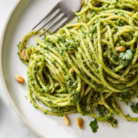 Creamy Sunflower Seed Pesto Pasta twirled on a fork, showcasing vibrant green sauce clinging to al dente noodles.  