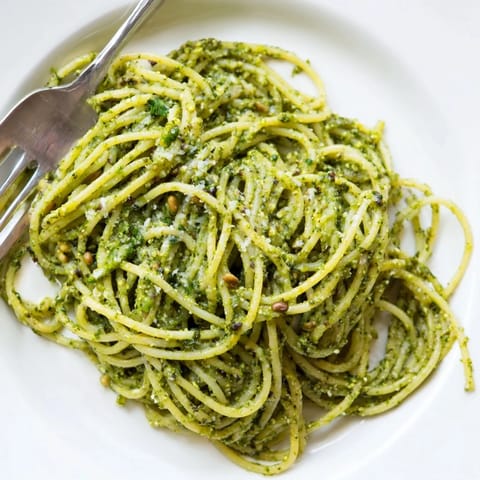 A comforting bowl of Creamy Sunflower Seed Pesto Pasta garnished with fresh basil leaves and grated Parmesan.  