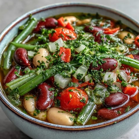 Homemade Three-Bean Salad Soup garnished with fresh parsley, served alongside crusty bread for dipping.