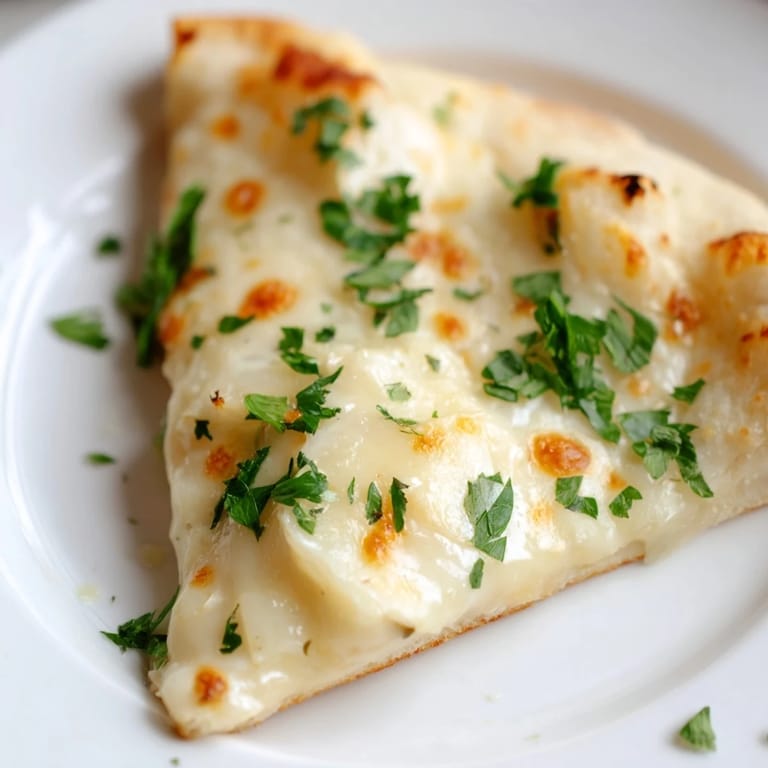 Fresh parsley garnish and olive oil brush shine on the crisp crust of Creamy Garlic White Pizza.