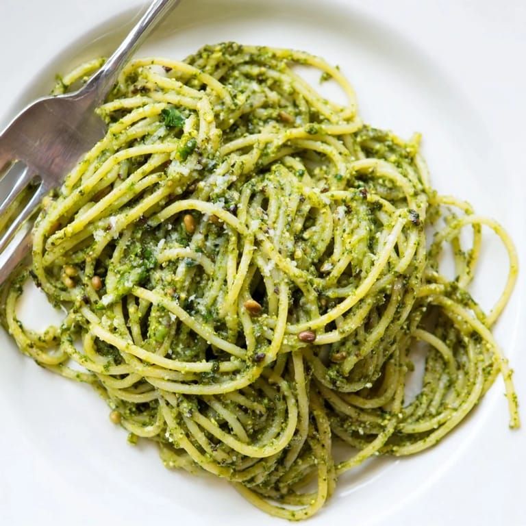 A comforting bowl of Creamy Sunflower Seed Pesto Pasta garnished with fresh basil leaves and grated Parmesan.  