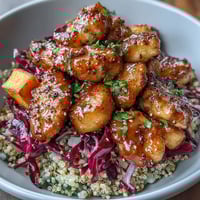 Hot honey chicken bowl with spiced chicken, roasted sweet potatoes, red cabbage slaw, and tangy hot honey mustard dressing.